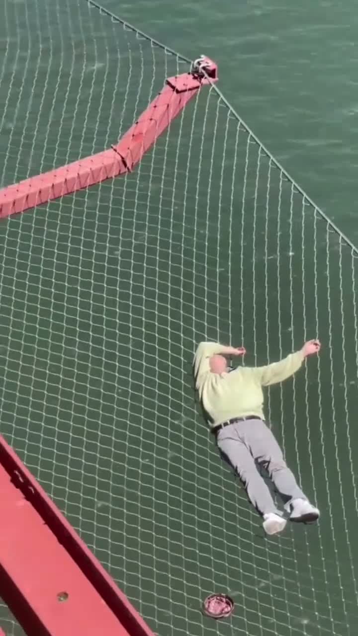 cover for Man seen laying down on the Golden Gate Bridge safety net.